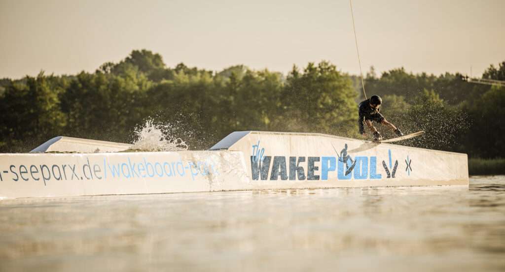 Wakeboarder springt über ein Hinterniss im Suesel Seeparx Wakeboardpark