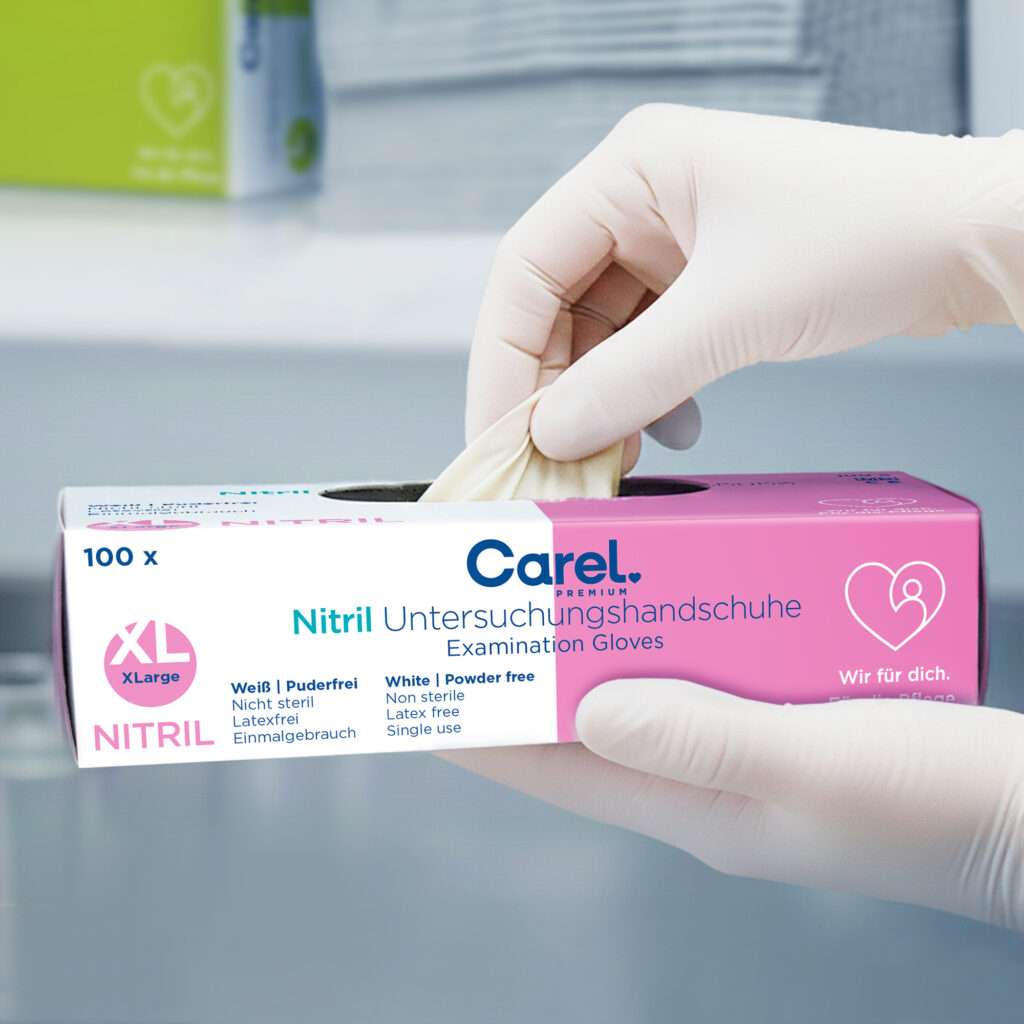 Aus der Carel Nitril-Untersuchungshandschuh Box Göße XL wird von einer Hand ein Handschuh aus der Spenderöffnung entnommen